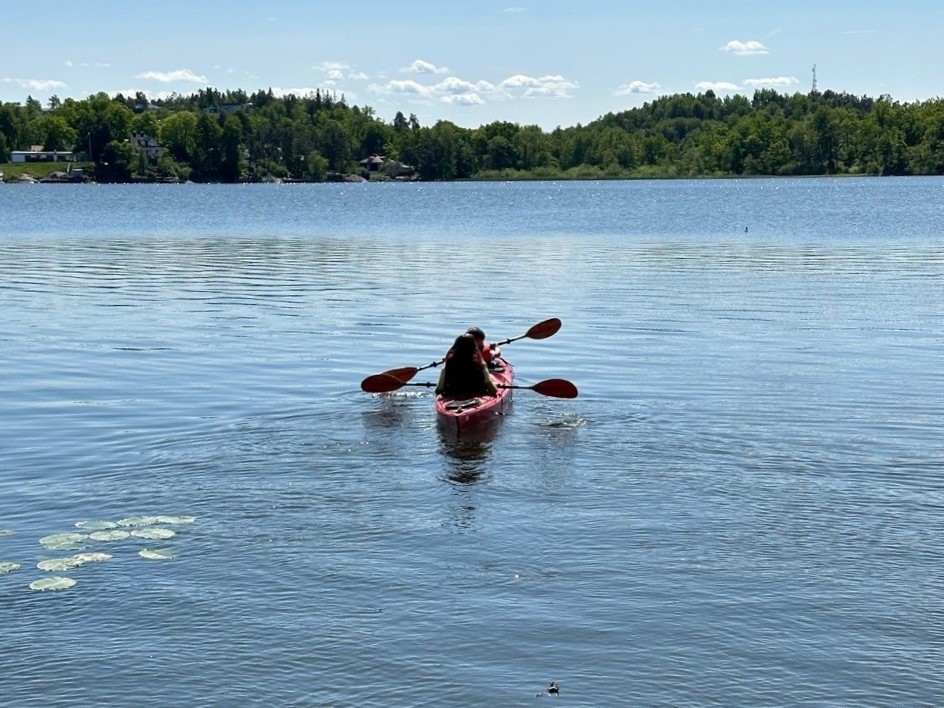 En tvåmanskajak med två paddlare på stilla sjö.